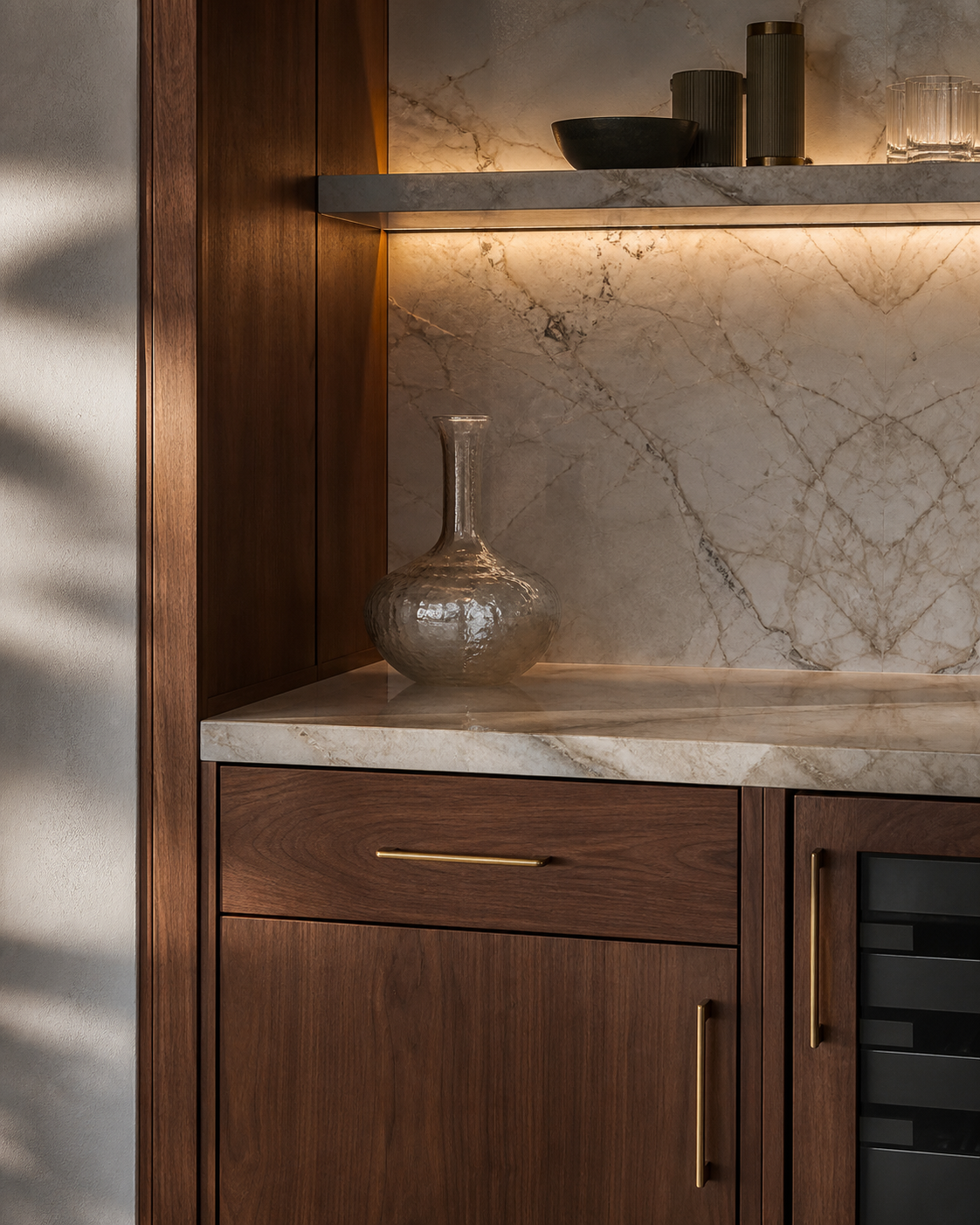 Natural stone, custom walnut millwork, and concealed architectural lighting detail